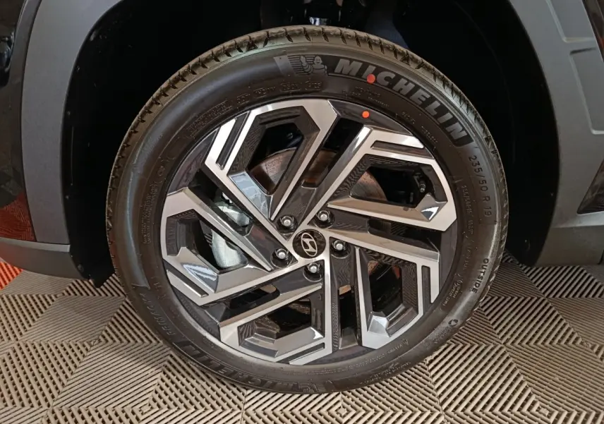 Gros plan sur la roue avant droite du Hyundai Tucson noir 2025, jante alliage au design géométrique et pneu Michelin.