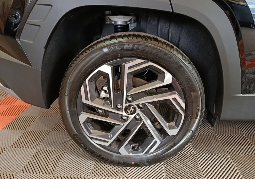 Gros plan sur la roue avant droite du Hyundai Tucson noir 2025 avec jante alliage au design géométrique.