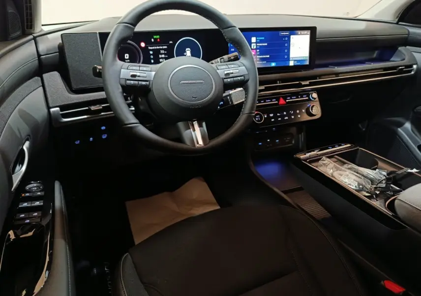 Vue intérieure avant du Hyundai Tucson 1.6 Hybrid noir, tableau de bord avec écran tactile et volant multifonctions cuir.