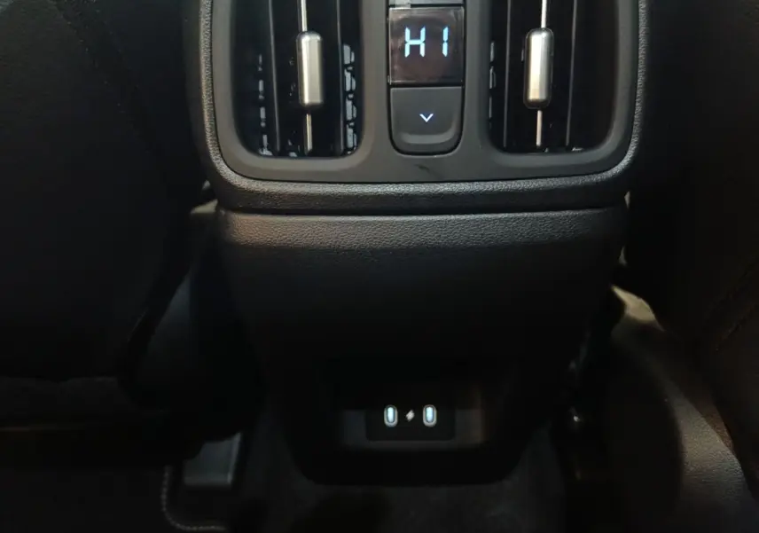 Vue rapprochée de la console arrière noire du Hyundai Tucson 1.6 Hybrid 2025 avec commandes de ventilation et ports USB.