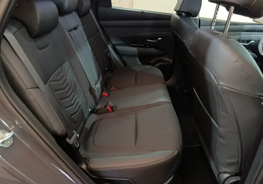 Vue côté gauche des sièges arrière noirs en tissu et cuir du Hyundai Tucson 1.6 Hybrid 2025 avec appuie-têtes réglables.