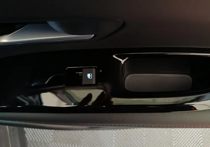 Gros plan sur le bouton de verrouillage des vitres côté gauche intérieur noir brillant du Hyundai Tucson 2025 hybride.