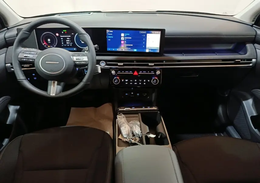 Vue intérieure avant du tableau de bord noir du Hyundai Tucson 2025 avec écran tactile large et volant multifonctions.