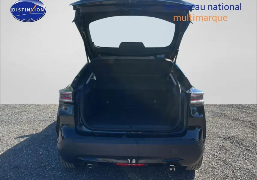 Vue arrière d'une Citroën C4 noire 2025 avec coffre ouvert sur un sol gravillonné.