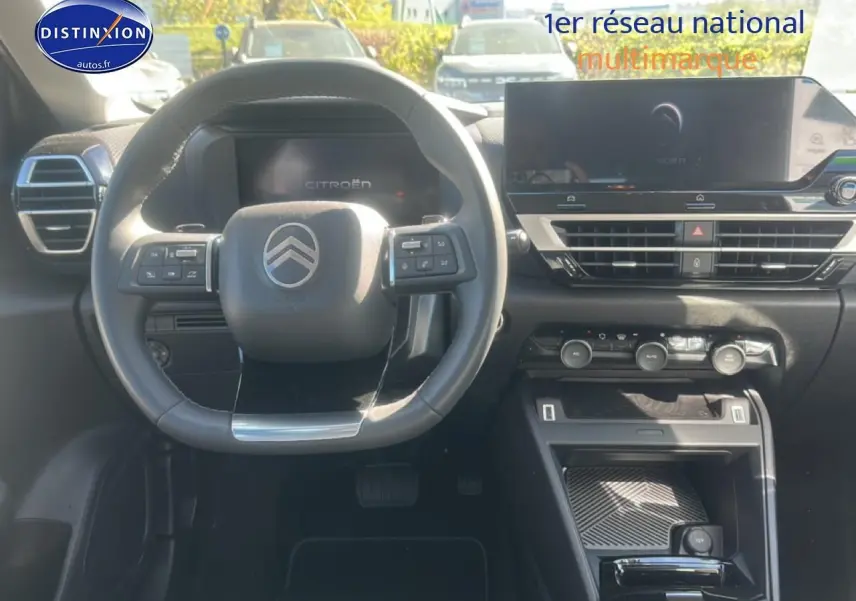 Vue intérieure avant du tableau de bord et volant cuir noir de la Citroën C4 hybride 2025 avec écran tactile et commandes au volant.