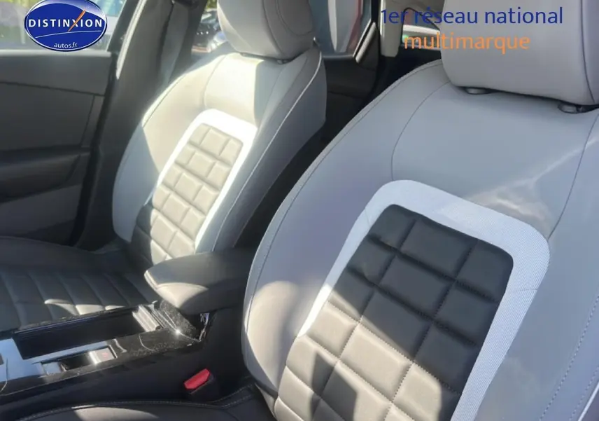 Vue rapprochée des sièges avant bi-ton gris clair et noir avec accoudoir central d'une Citroën C4 hybride 2025.