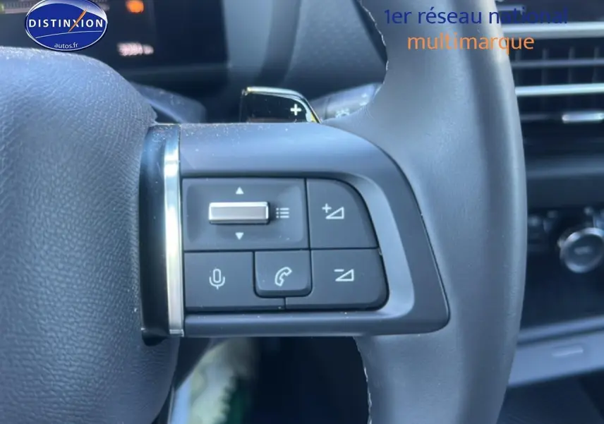 Gros plan sur les commandes au volant cuir noir de la Citroën C4 hybride 2025, avec boutons de volume et appel.