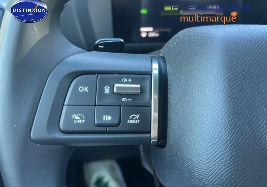 Gros plan sur les commandes au volant côté gauche d'une Citroën C4 noire hybride 2025, avec boutons de régulateur et assistant.