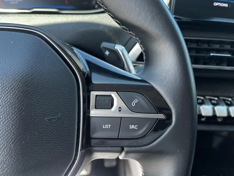 Gros plan sur les commandes au volant côté gauche du Peugeot 3008 noir, avec palettes de changement de vitesse visibles.
