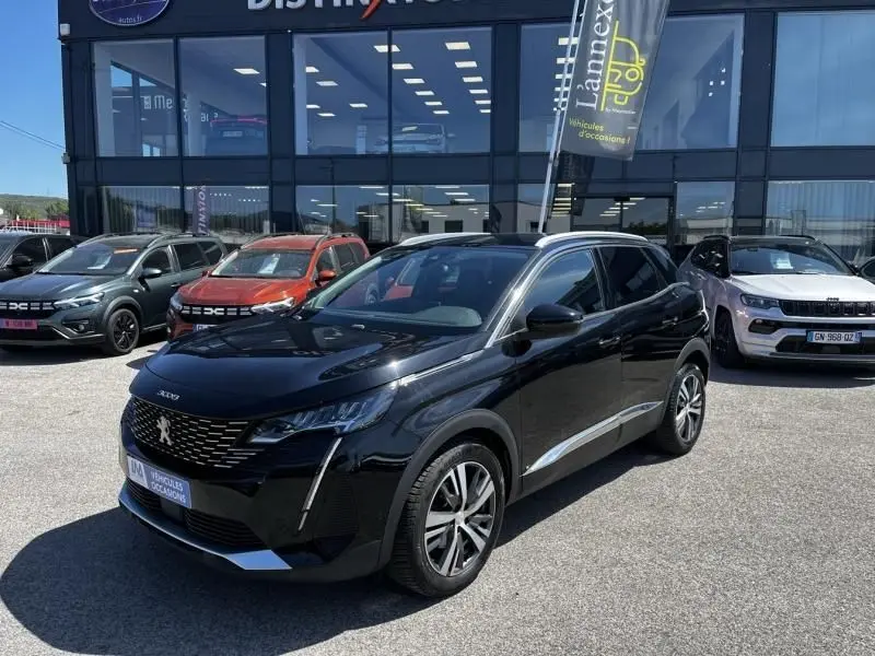 Peugeot 3008 noir vue 3/4 avant droit, avec calandre distinctive et jantes alliage, stationné devant un showroom.