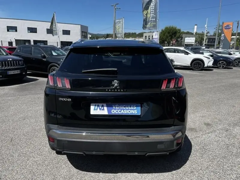 Vue arrière d'un Peugeot 3008 noir 2021 avec feux arrière à griffes distinctifs sur un parking extérieur.
