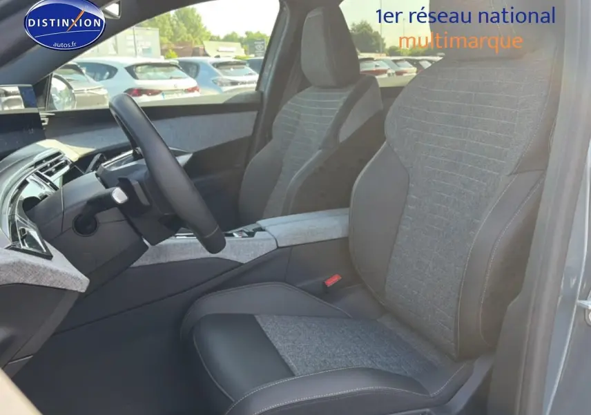 Vue intérieure côté conducteur du Peugeot 3008 bleu 2025, sièges tissu et cuir avec accoudoir central gris.