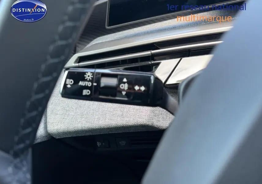 Détail du commodo d'éclairage à gauche du volant dans l'habitacle du Peugeot 3008 bleu 2025.