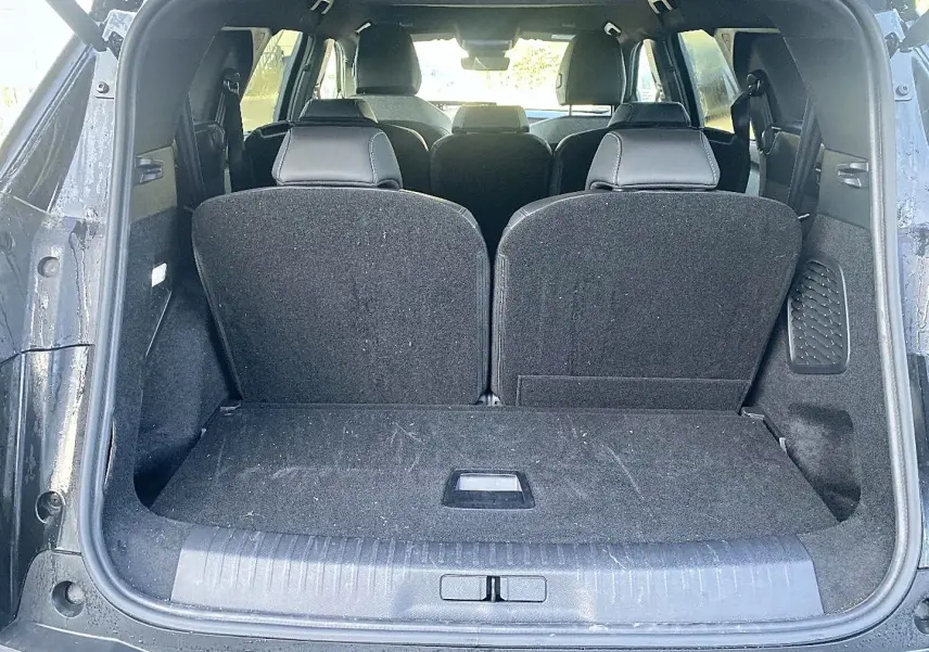 Vue arrière du coffre ouvert du Peugeot 5008 noir, montrant les sièges arrière relevés et l'espace de chargement.