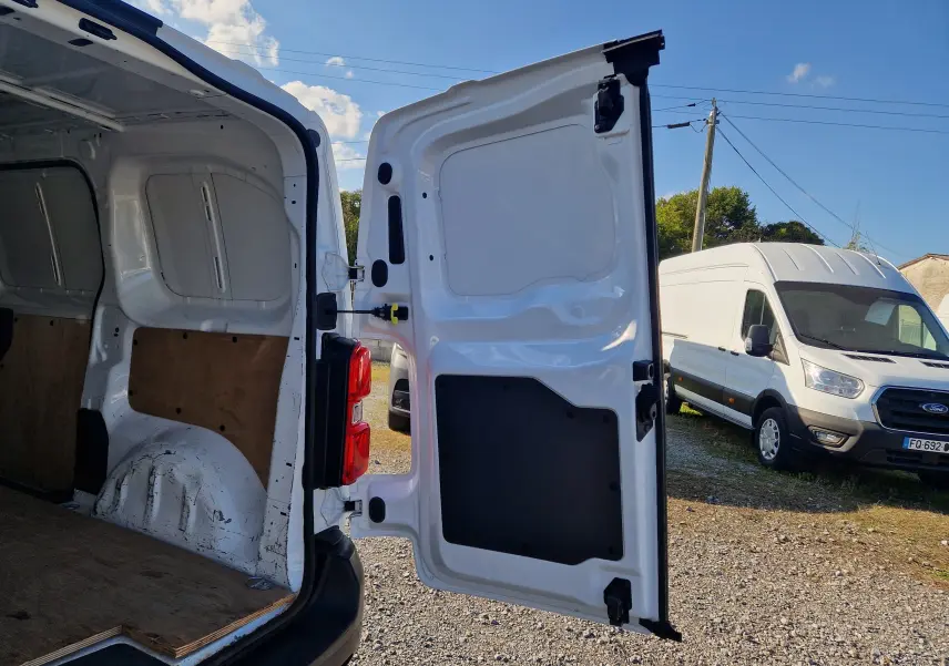 Vue arrière gauche du Peugeot Expert Fourgon blanc 2020 avec porte ouverte montrant l'intérieur utilitaire vide et plancher bois.