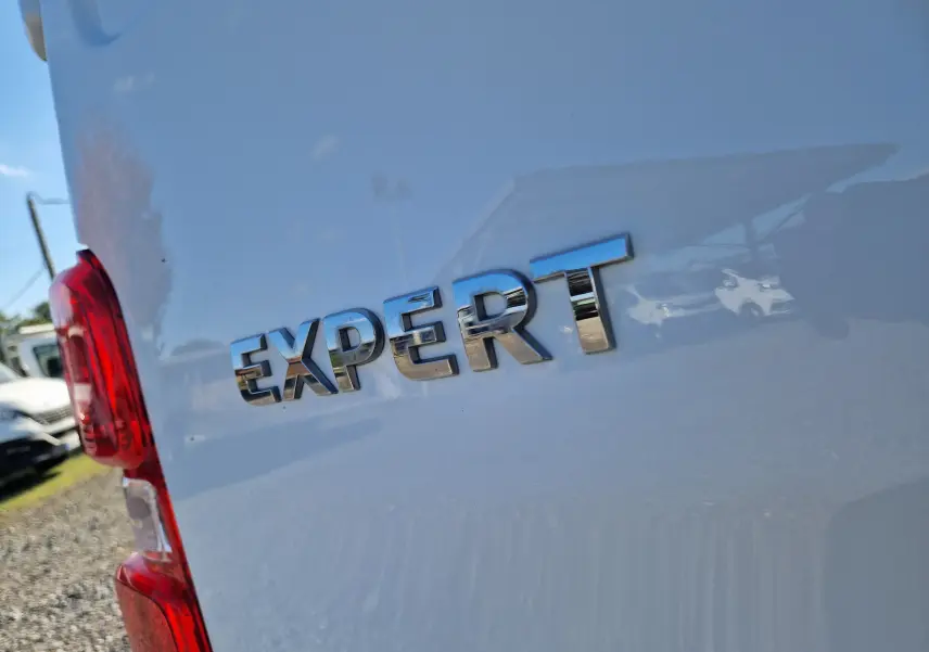 Gros plan sur l'arrière gauche blanc du Peugeot Expert Fourgon avec le logo "EXPERT" en relief chromé.