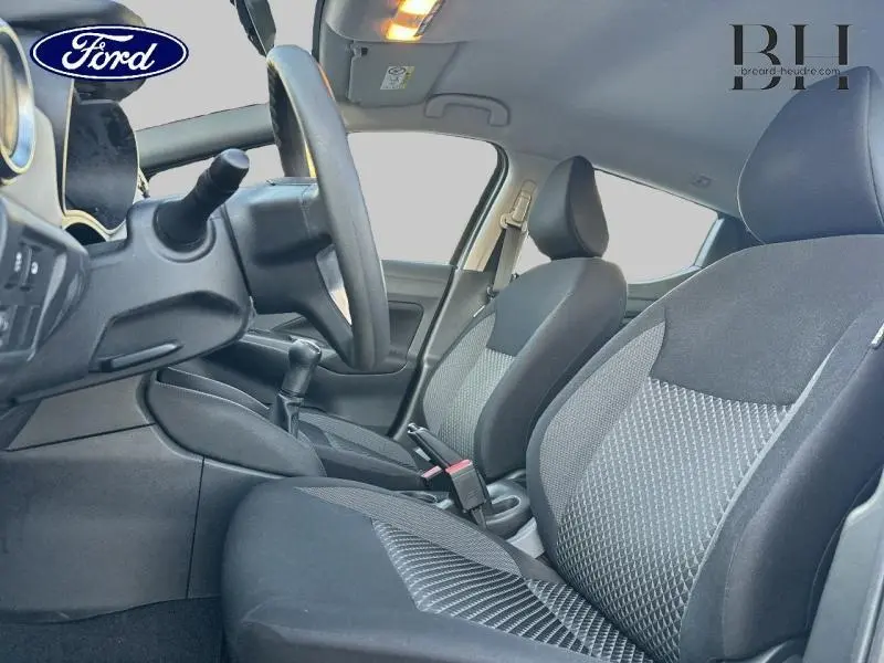 Intérieur avant de la Nissan Micra 2018 gris acier, vue côté conducteur montrant sièges tissu noir et volant.