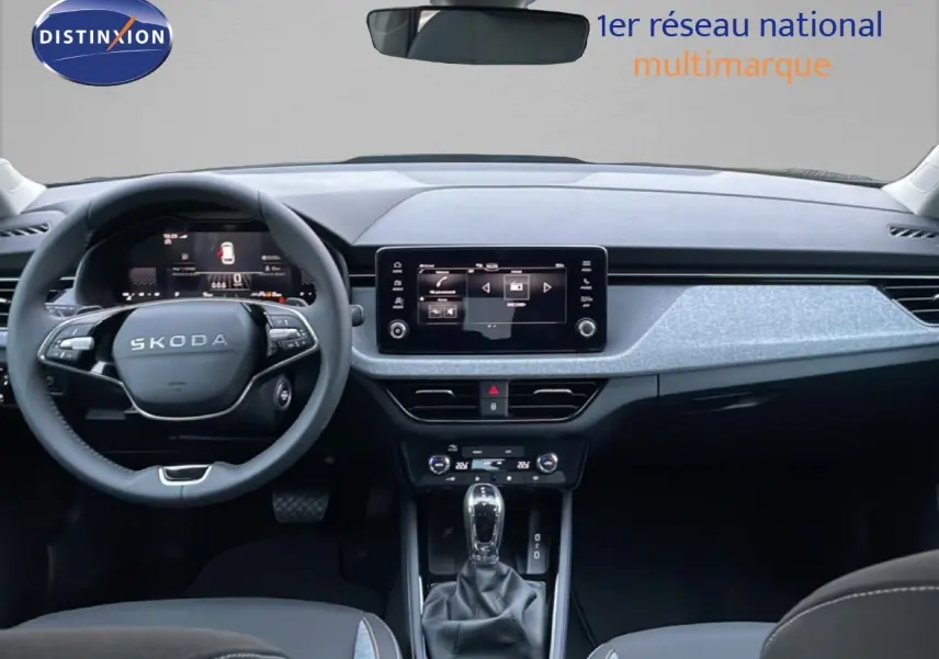 Vue intérieure frontale du tableau de bord gris clair et noir du Skoda Kamiq 2025 avec écran tactile et volant multifonction.
