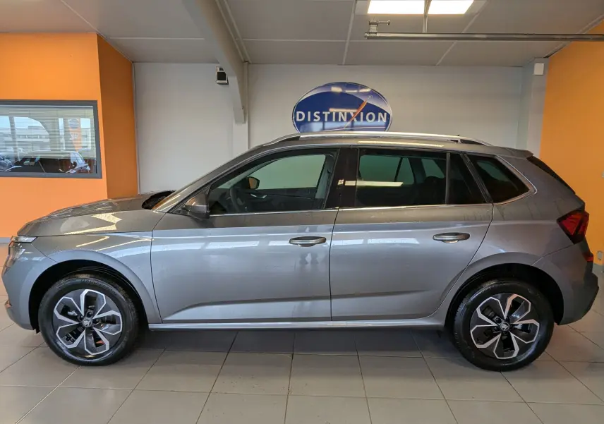 Vue latérale droite d'un Skoda Kamiq gris graphite métal 2025 en intérieur, avec jantes alliage et toit ouvrant.