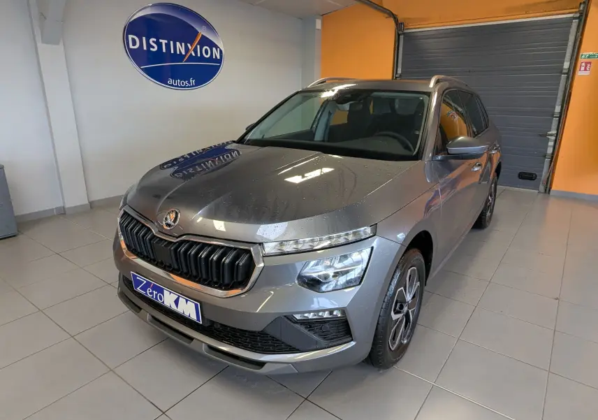 Vue 3/4 avant droite d'un Skoda Kamiq gris graphite métallisé avec calandre noire et jantes alliage en showroom.