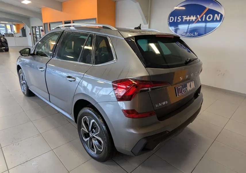Vue 3/4 arrière droite d’un Skoda Kamiq gris graphite métal 2025 avec jantes alliage et feux LED, en intérieur showroom.