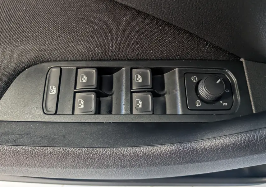 Gros plan sur les commandes de lève-vitres et réglage des rétroviseurs côté conducteur d’une Skoda Kamiq gris graphite.