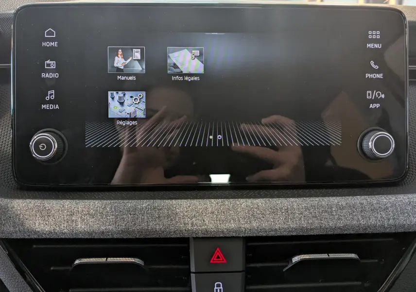 Écran tactile central du Skoda Kamiq 2025, interface affichant les menus, entouré de commandes rotatives, finition intérieure gris graphite.