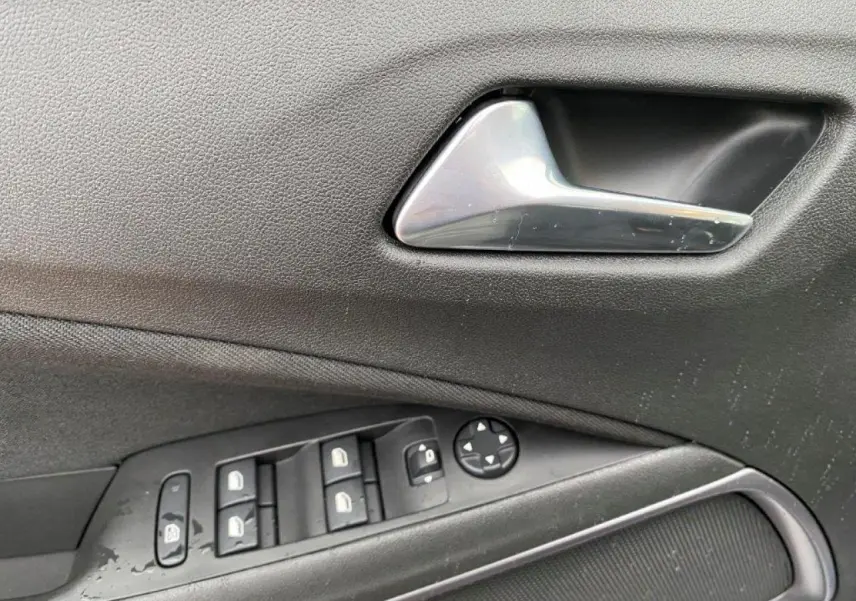 Gros plan sur la poignée intérieure et les commandes des vitres côté conducteur d'un Opel Crossland gris métallisé.