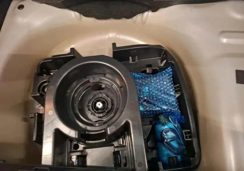 Gros plan sur le rangement sous plancher de coffre d'une Citroën C3 2024 gris foncé, montrant un support et accessoires emballés.