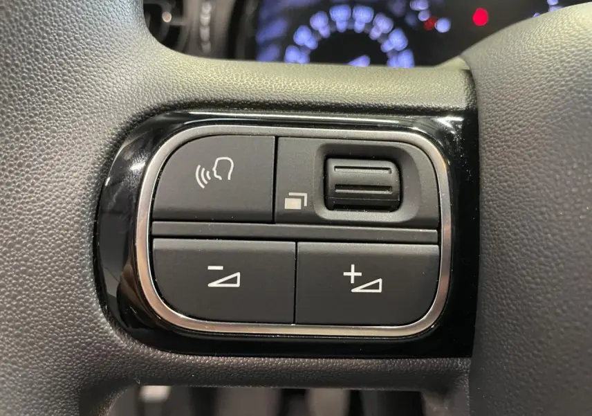 Gros plan sur les commandes audio au volant de la Citroën C3 2024, finition noir brillant avec surpiqûres jaunes.