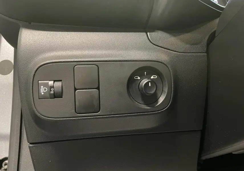Vue rapprochée des commandes de réglage des phares et des rétroviseurs côté gauche d'une Citroën C3 gris foncé 2024.