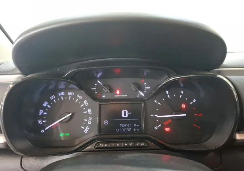 Vue rapprochée du tableau de bord de la Citroën C3 2024 gris foncé, affichant la vitesse à zéro et divers témoins allumés.