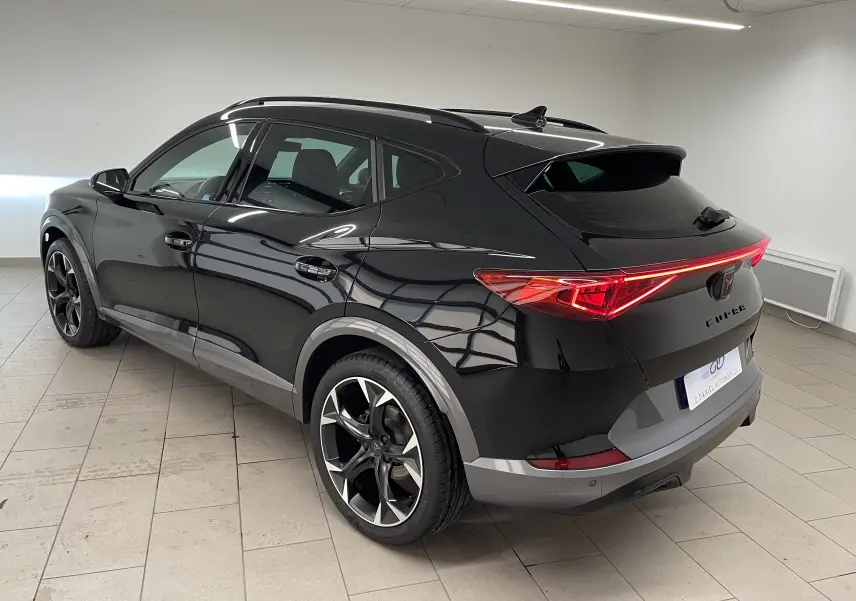 Vue 3/4 arrière côté gauche d'un CUPRA Formentor Noir Minuit avec feux arrière allumés et jantes noires sport