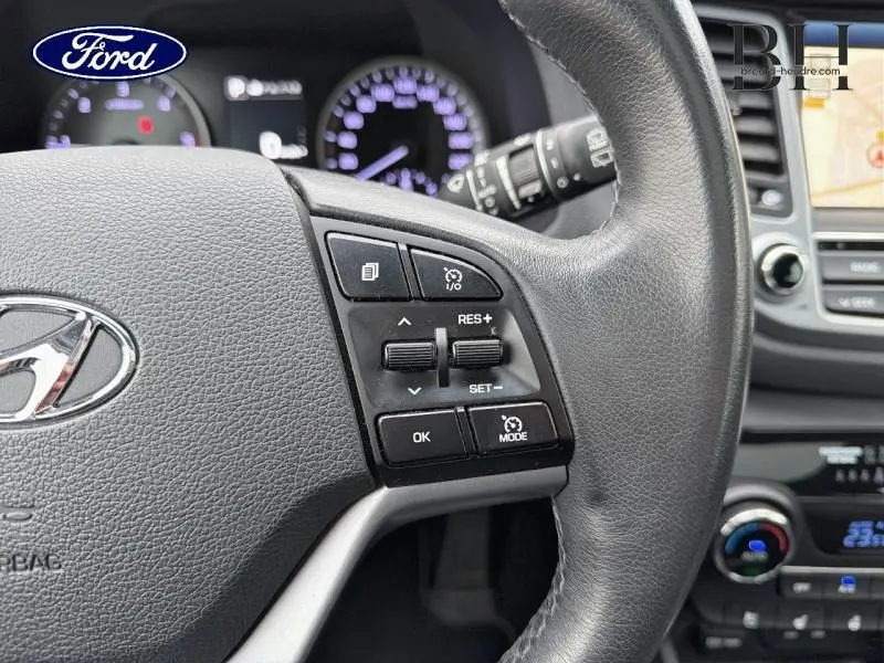 Gros plan sur le volant cuir du Hyundai Tucson Phantom Black 2018, avec commandes multifonctions et tableau de bord en arrière-plan.