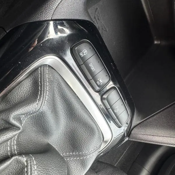 Gros plan sur la console centrale de l’Opel Corsa gris clair 2022, montrant le soufflet de levier de vitesses et les boutons de mode conduite.