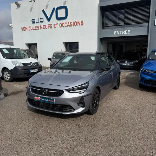 Opel Corsa gris clair 2022 en 3/4 avant droit, finition GS Line avec jantes noires, devant un garage Sud VO.