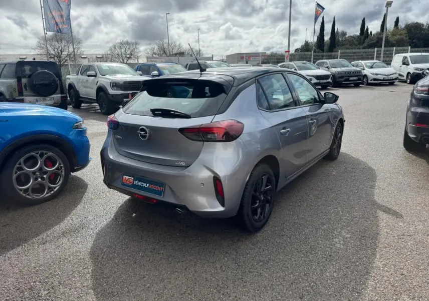 Opel Corsa 1.2 Turbo gris clair vue 3/4 arrière droit, avec toit noir et jantes noires, sur parking extérieur.
