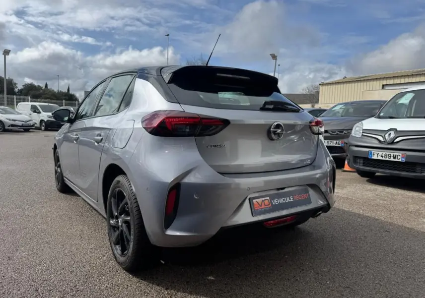 Vue 3/4 arrière droite d'une Opel Corsa gris clair 2022 avec jantes noires et badge GS Line visible au parking.