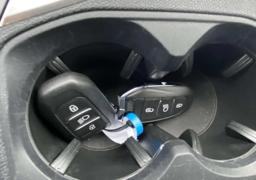 Gros plan sur les clés de la Peugeot 3008 posées dans un porte-gobelets noir à l'intérieur du véhicule.
