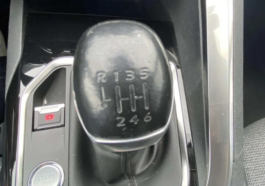 Gros plan sur le levier de vitesse manuel noir de la Peugeot 3008 blanc nacré, entouré de finitions chromées et tissu gris.