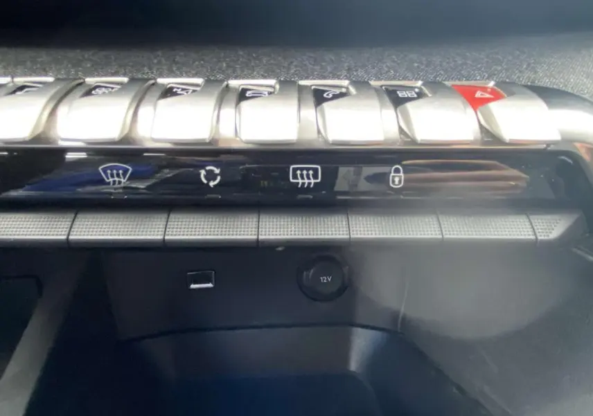 Gros plan sur les commandes centrales et prise 12V du tableau de bord du Peugeot 3008 blanc de 2017.