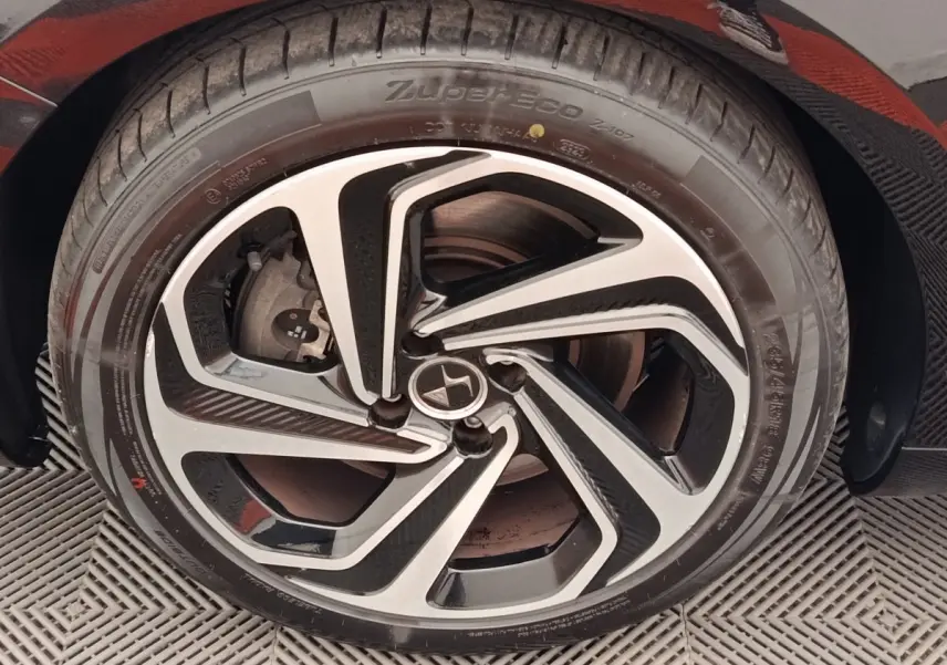 Gros plan sur la roue avant droite d'une DS5 noire, mettant en valeur la jante en alliage au design moderne bicolore.