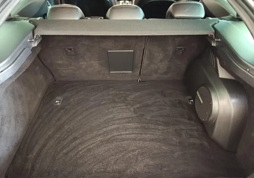 Coffre spacieux noir du DS5 BlueHDi 180 vu de l'intérieur arrière, avec banquette arrière et enceinte intégrée visible.