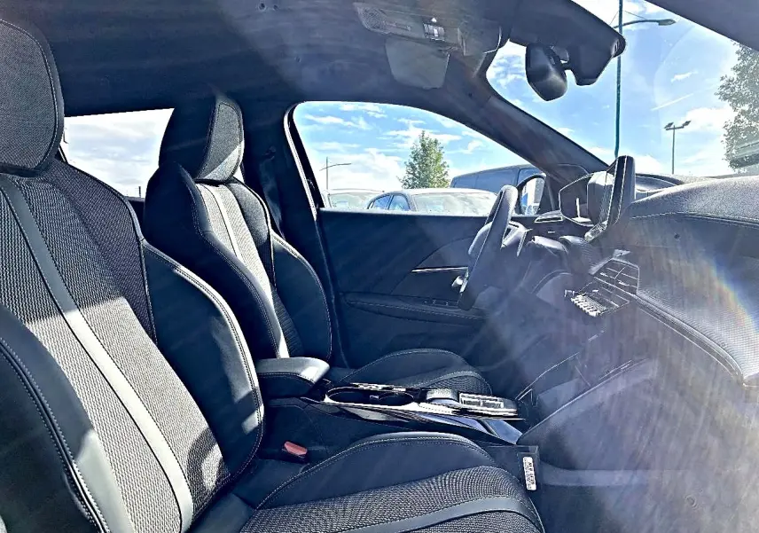 Intérieur avant du Peugeot 2008 1.2 hybrid 145 GT noir, sièges sport et tableau de bord moderne côté conducteur.