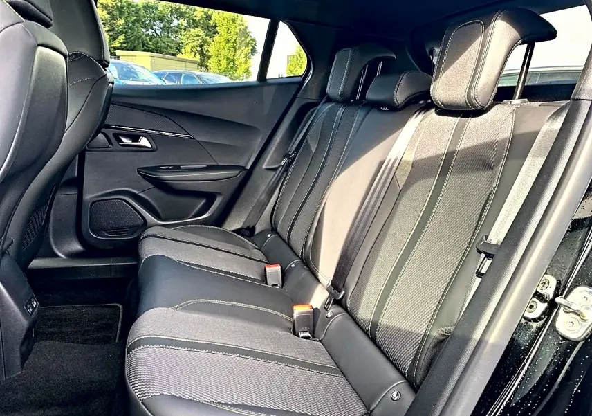 Vue latérale intérieure du siège arrière noir de la Peugeot 2008 1.2 hybrid 145 GT e-DCS6 avec surpiqûres contrastantes.