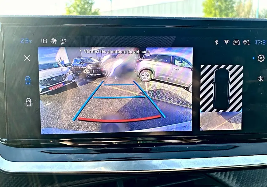 Écran tactile montrant la caméra de recul d'une Peugeot 2008 noire, avec guidage de trajectoire en bleu et rouge.
