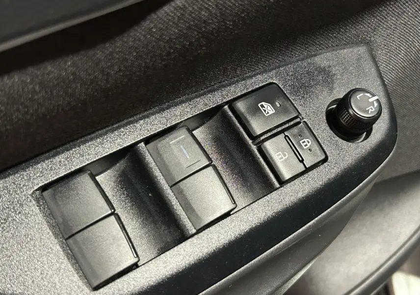 Gros plan sur les commandes des vitres et rétroviseurs côté conducteur de la Toyota Yaris Cross 2025 gris minéral.