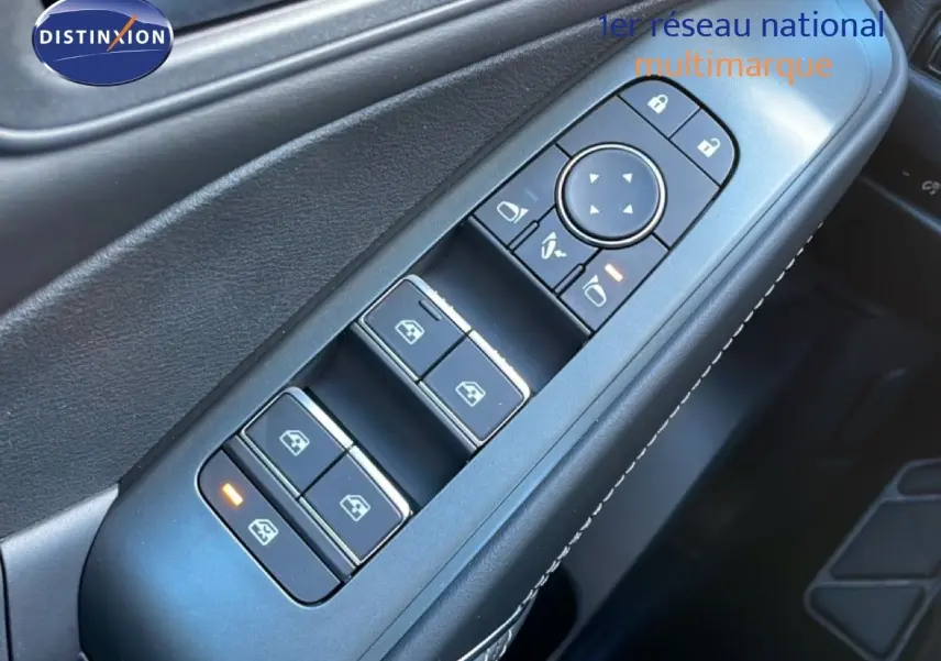 Gros plan sur les commandes des vitres côté conducteur du Nissan Qashqai gris argile métal, avec éclairage orange sur un bouton.