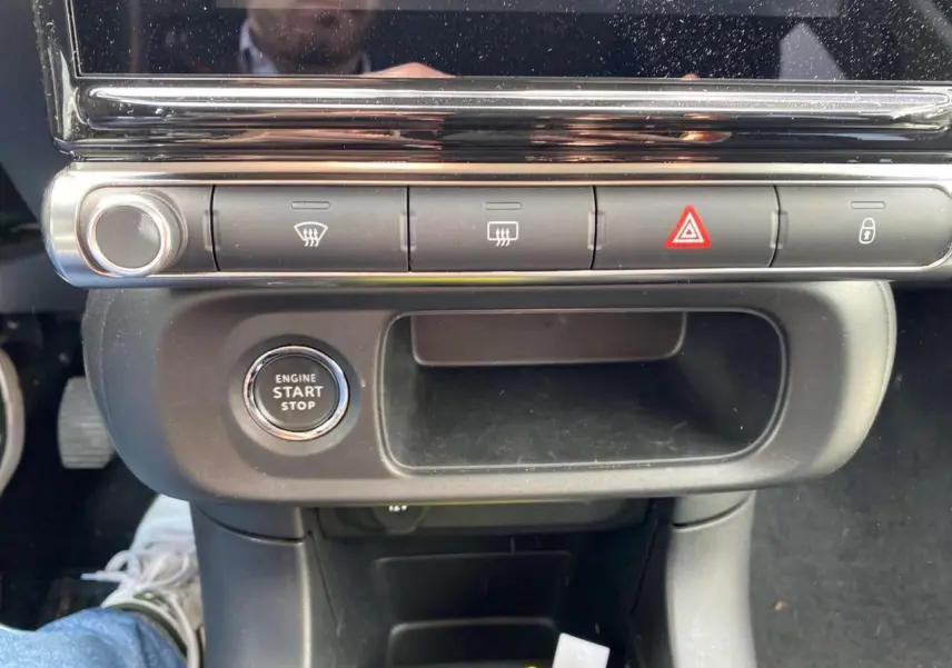 Vue rapprochée du bouton start/stop et des commandes de climatisation sur la console centrale de la Citroën C3 2021.
