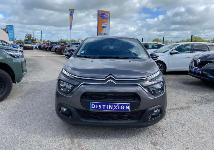 Vue avant d'une Citroën C3 gris platinium avec calandre et phares distinctifs sur un parking extérieur.
